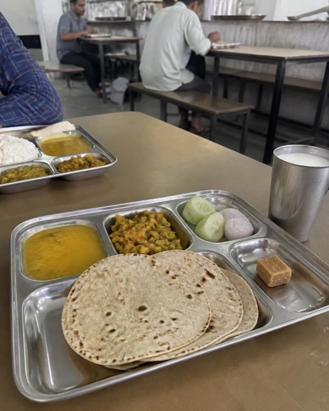 Roti, dal, sabzi and rice on a steel compartment tray in a canteen