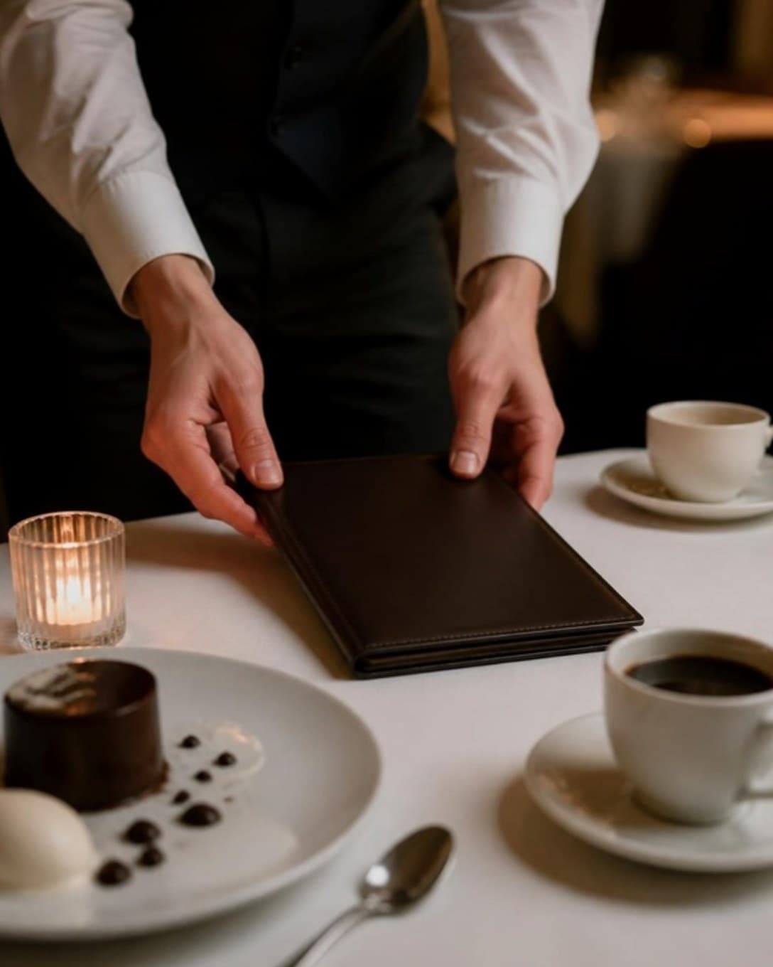 Waiter placing a bill folder on a dining table