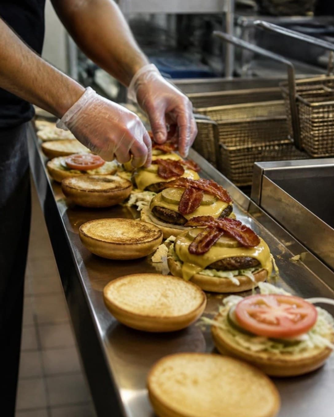 Hands assembling burgers on a kitchen line