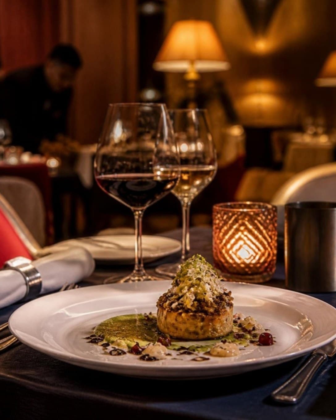 Plated dish and wine glasses on a candle-lit dining table